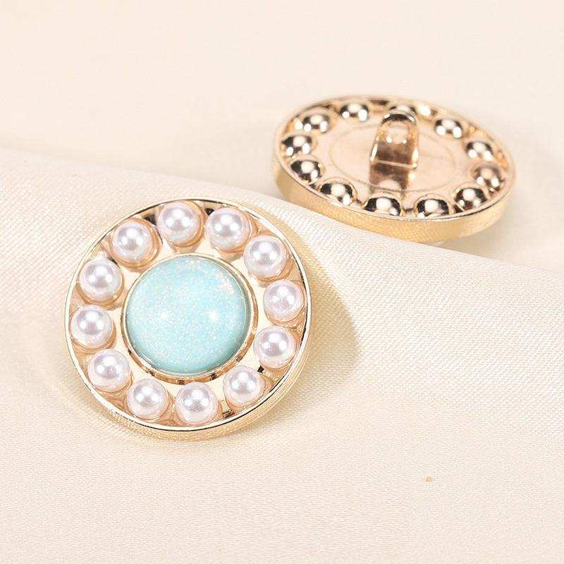Round pearl resin button, light blue center with gold rim; front view with back shank showing