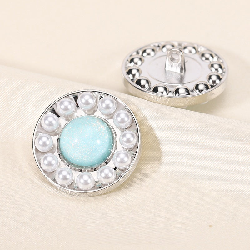Round pearl resin button, light blue center with silver rim; front view with back shank showing