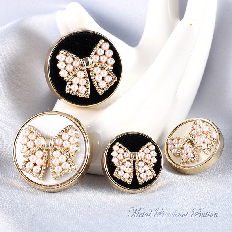 Gold bowknot button with white faux pearl clusters, rhinestone border, dark backing