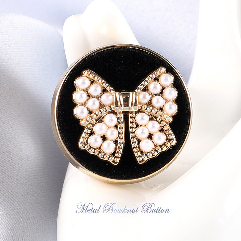 Gold bowknot metal button with white faux pearls on dark backing, rhinestone details
