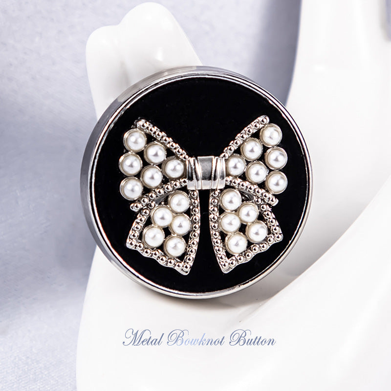 Silver metal shank bowknot button with white faux pearl clusters on dark backing