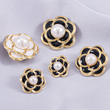 Black camellia metal shank button with round white pearl center and gold-tone frame