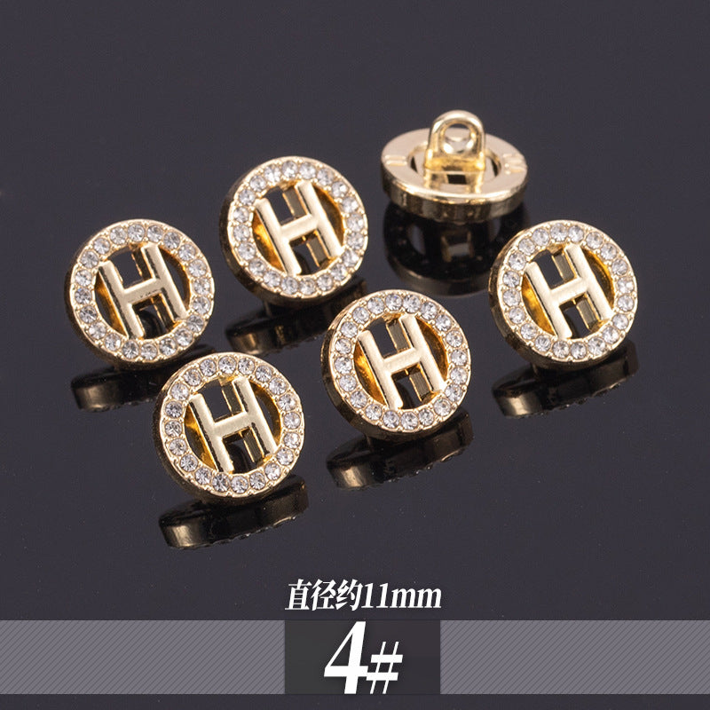 Golden rhinestone shirt buttons with H-style monogram cutout in round crystal border; 11-13mm