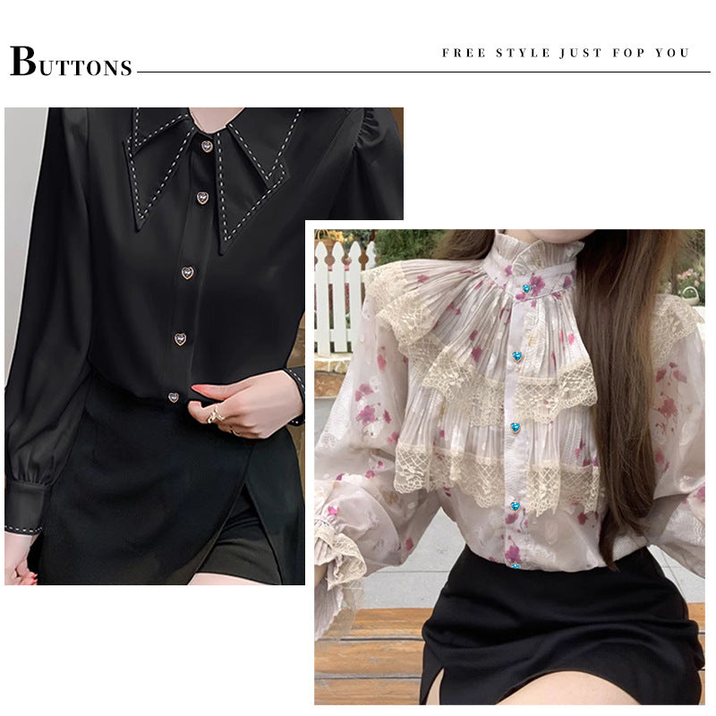Heart-shaped crystal buttons on a black shirt front, blue and green stones in gold frames