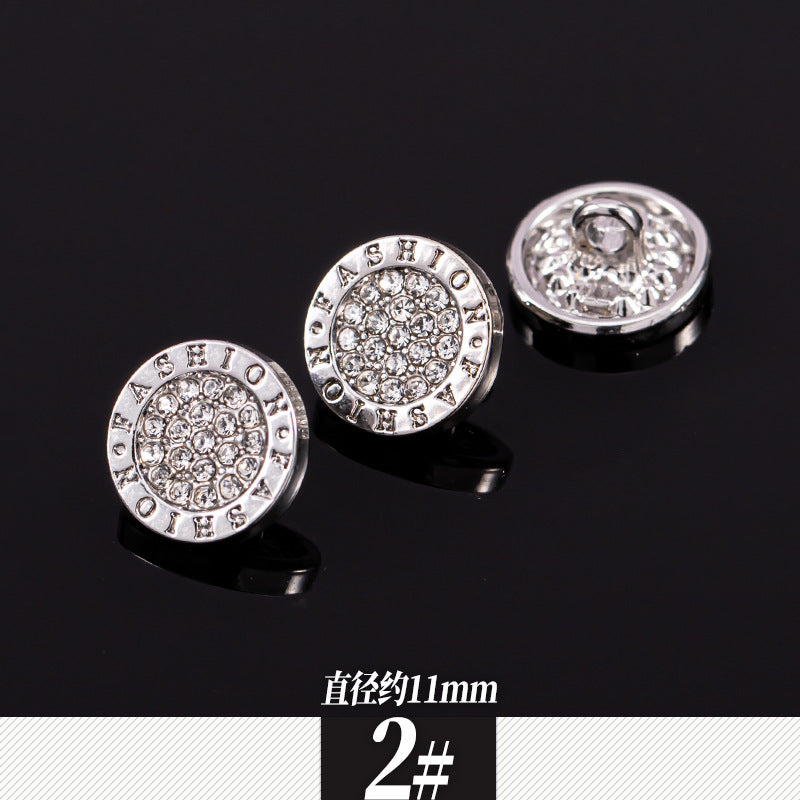 Two round silver rhinestone shirt buttons with wordlike border detailing