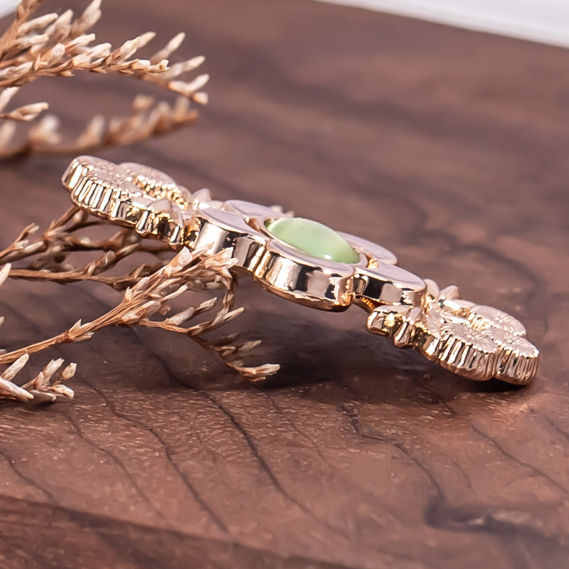 Gold-tone branch flower metal lock button with green cat’s eye center stone