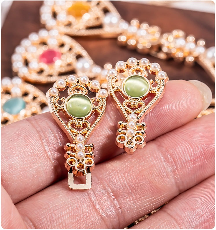 Mini close-up: pipa-shaped metal buttons with green oval stones and pearl frames