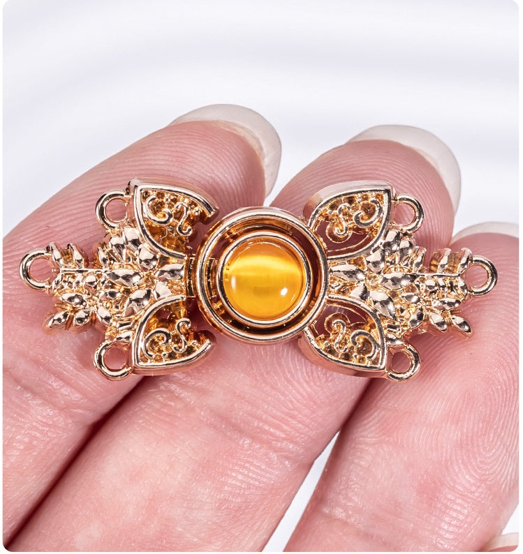 Close-up cat’s eye stone metal buckle, orange-gold center with gold filigree edges.