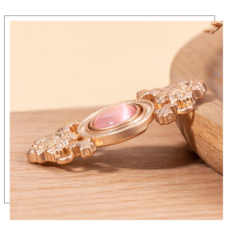 Close-up lotus cat’s eye lock button with pink oval stone and rose-gold metal petals