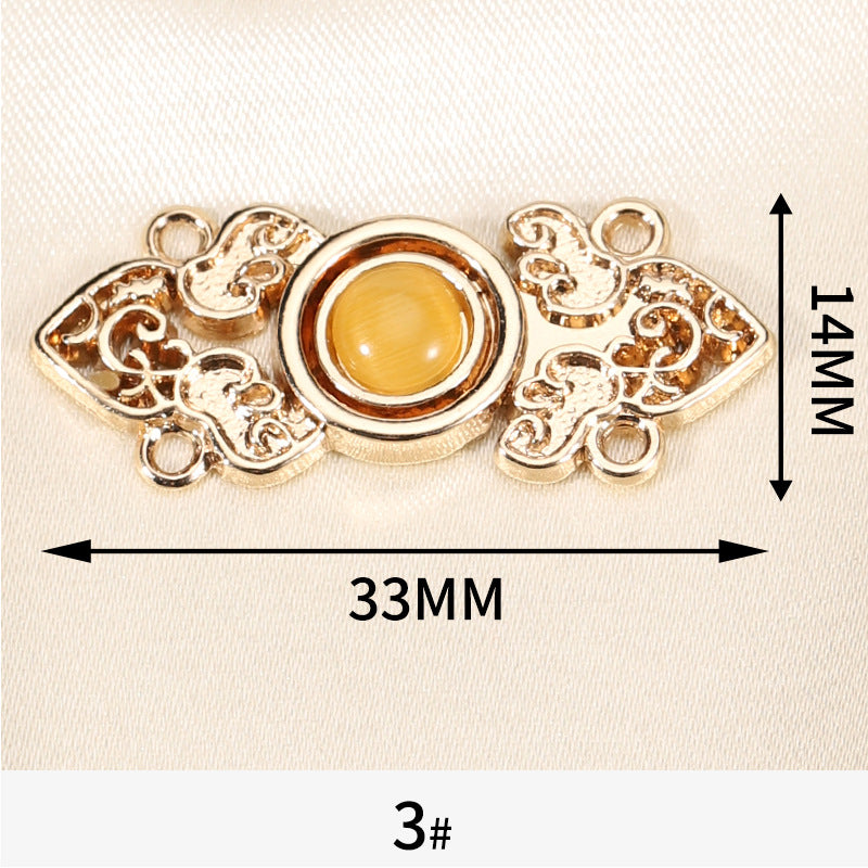 Maßangabe: goldfarbener Zierknopf mit gelbem Katzenauge-Stein, 33mm breit
