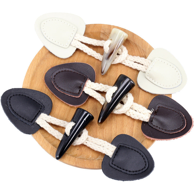 Genuine leather horn toggle buttons in black and cream on a wooden display board, 5 pcs