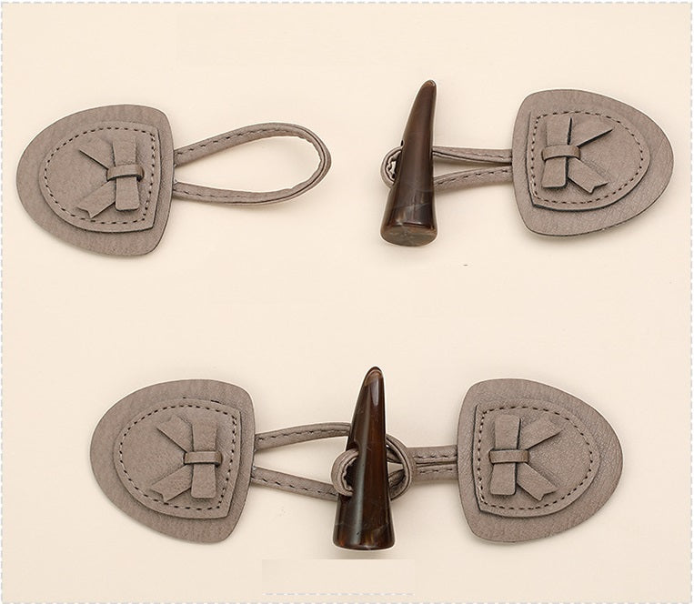 Pair of gray leather horn buttons with horn shank and stitched flap