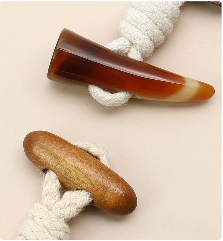 Horn shank with braided cord for leather coat buttons; amber and cream tones