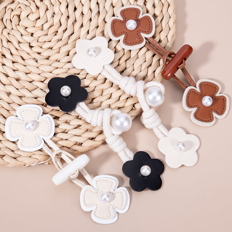 12-piece set of faux leather flower toggle buttons in white, black, and brown with pearl accents