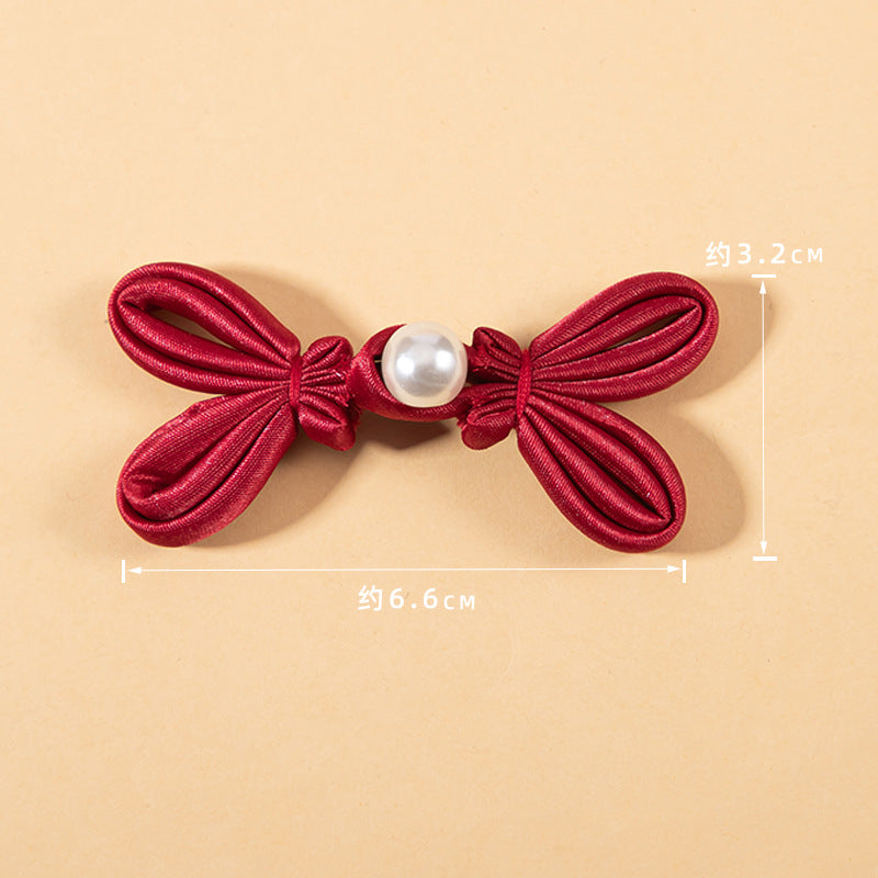 Red satin bowknot button with round pearl bead center, approx 6.6 cm wide