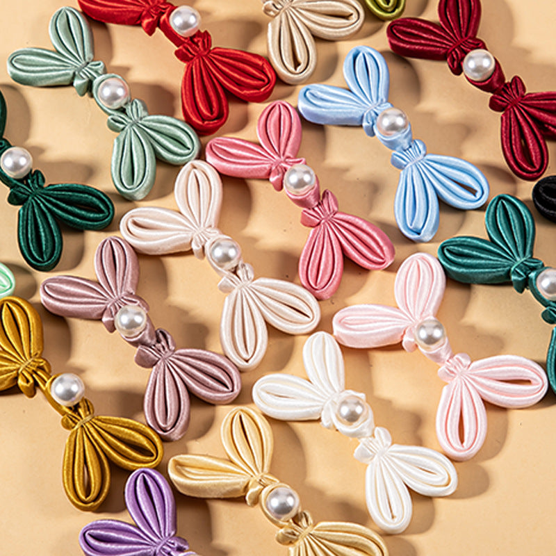 Mixed-color satin bowknot pearl buttons with round pearl centers, close-up assortment