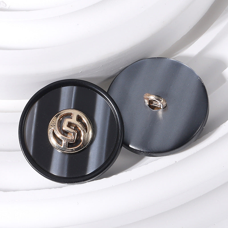 18–25mm round resin buttons, black with gold-tone geometric linked pattern, shank view