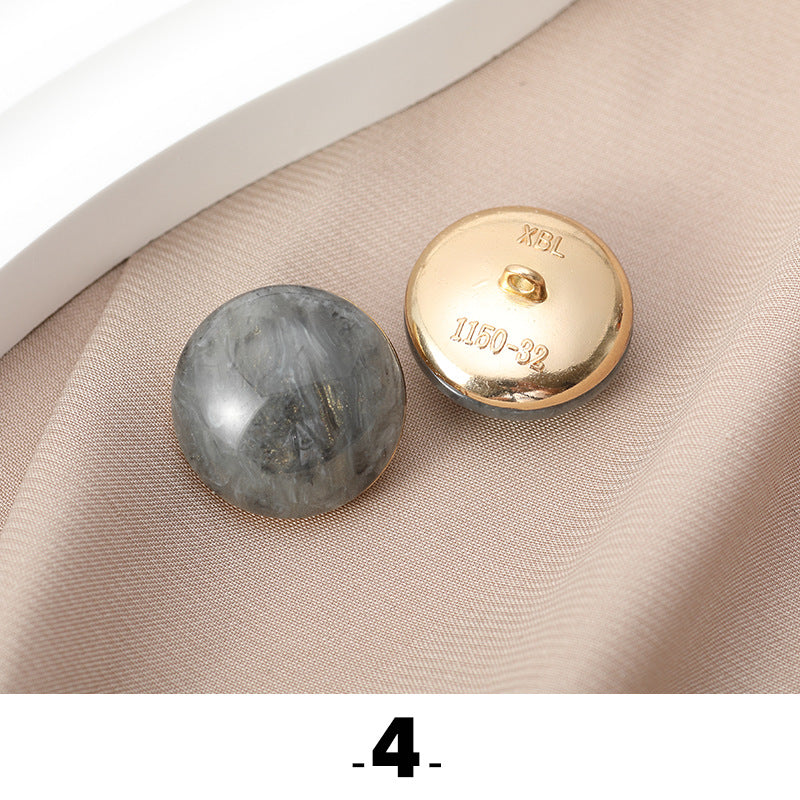 Gray cat’s eye resin button with gold metal base, back side facing up