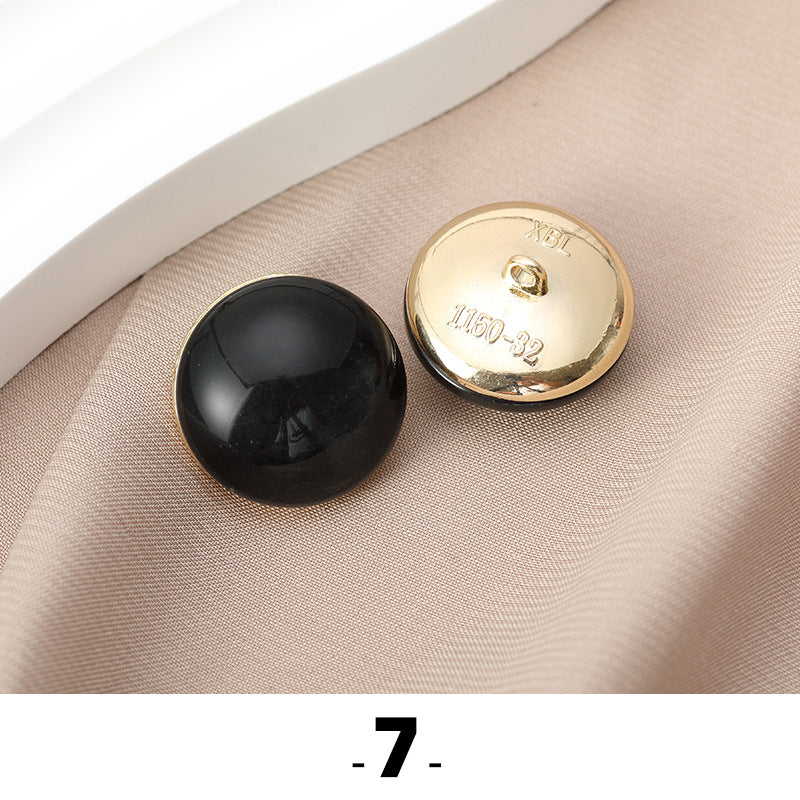 Black cat’s eye resin button with gold metal base, back side facing up