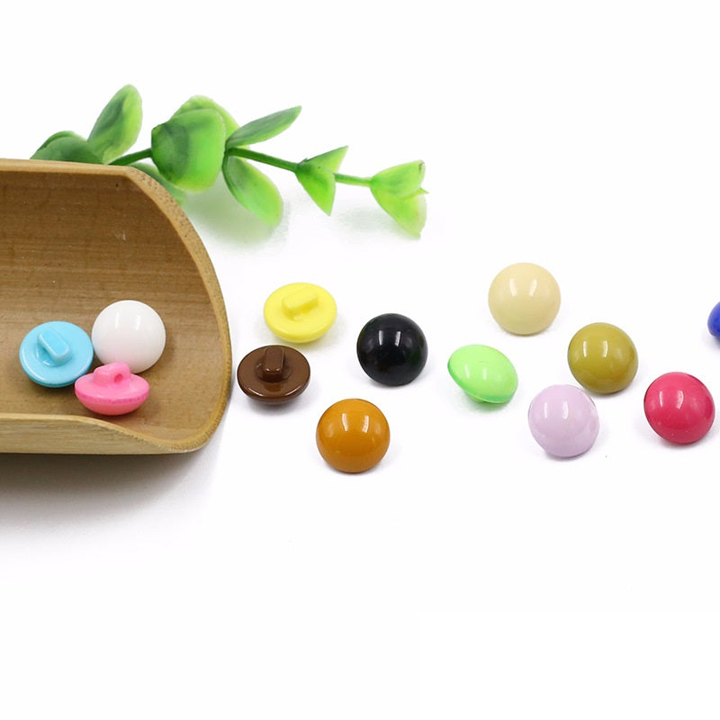 Round mushroom resin buttons in candy colors with flat backs, in a wooden tray