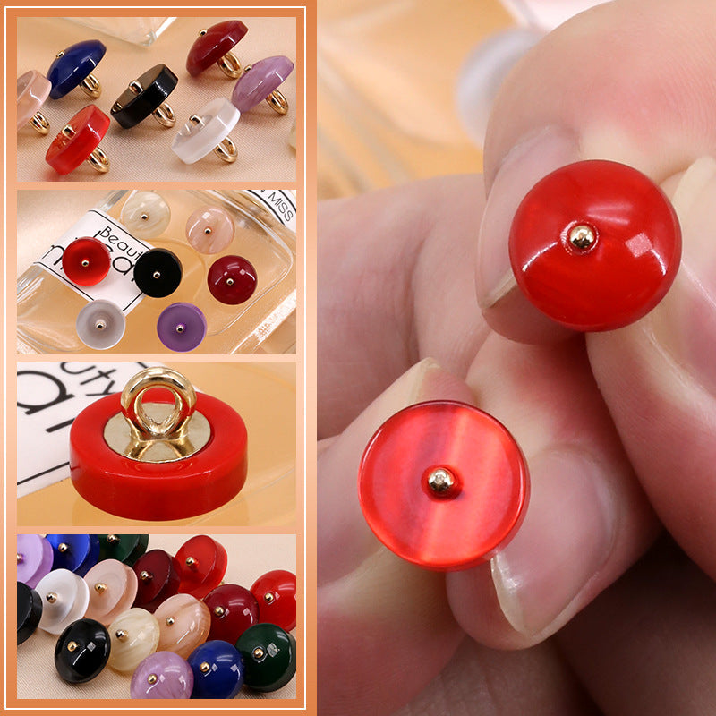 Close-up red round resin button with metal shank and gold-tone shank loop
