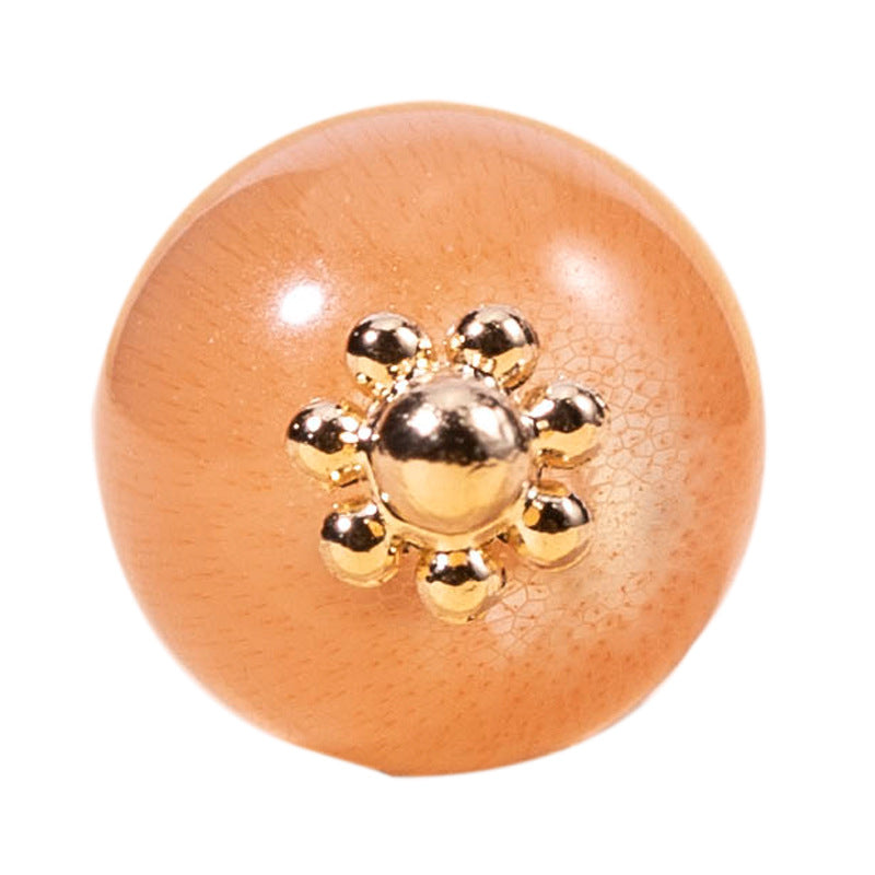 Close-up of round cat’s eye stone button in orange with gold-tone filigree