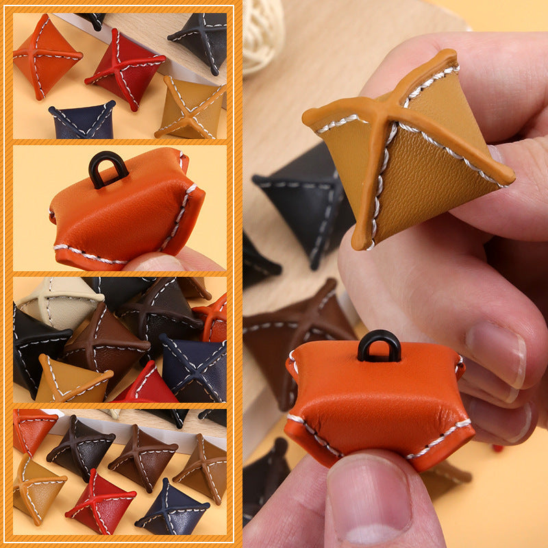 Orange rhombus leather button with black loop shank and contrast stitching