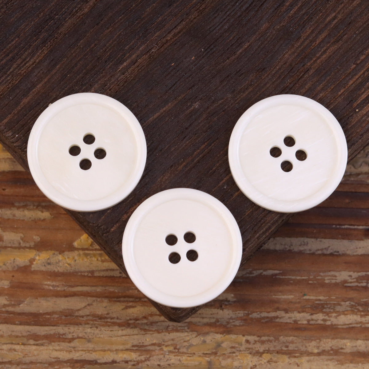 Set of 4-hole bone buttons in light ivory, wide edge, front perspective