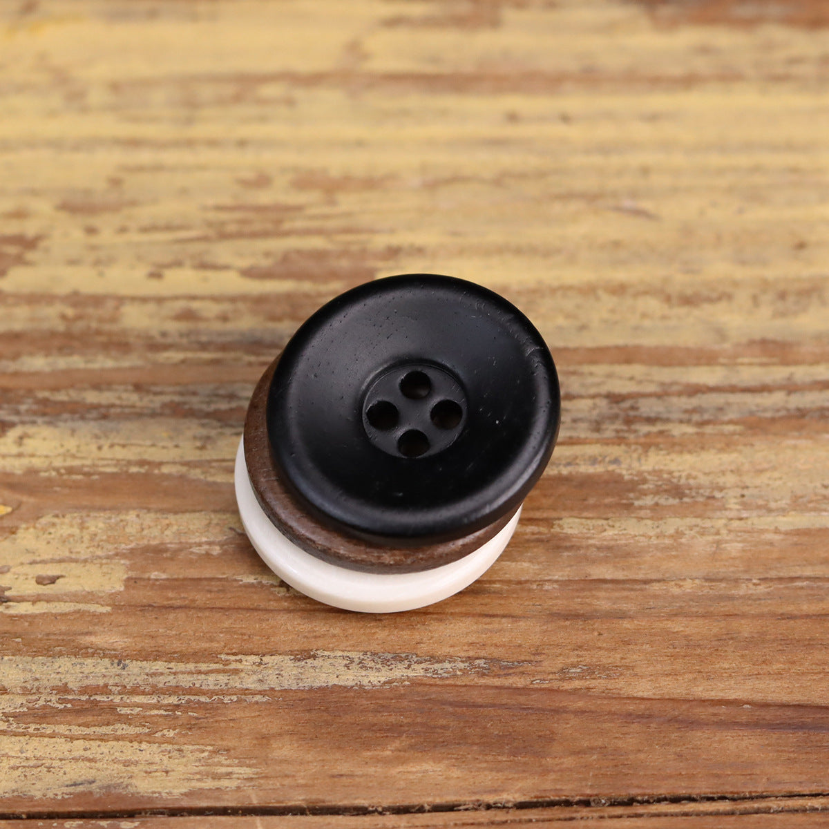 Black 4-hole bowl-shaped distressed bone button with white backing