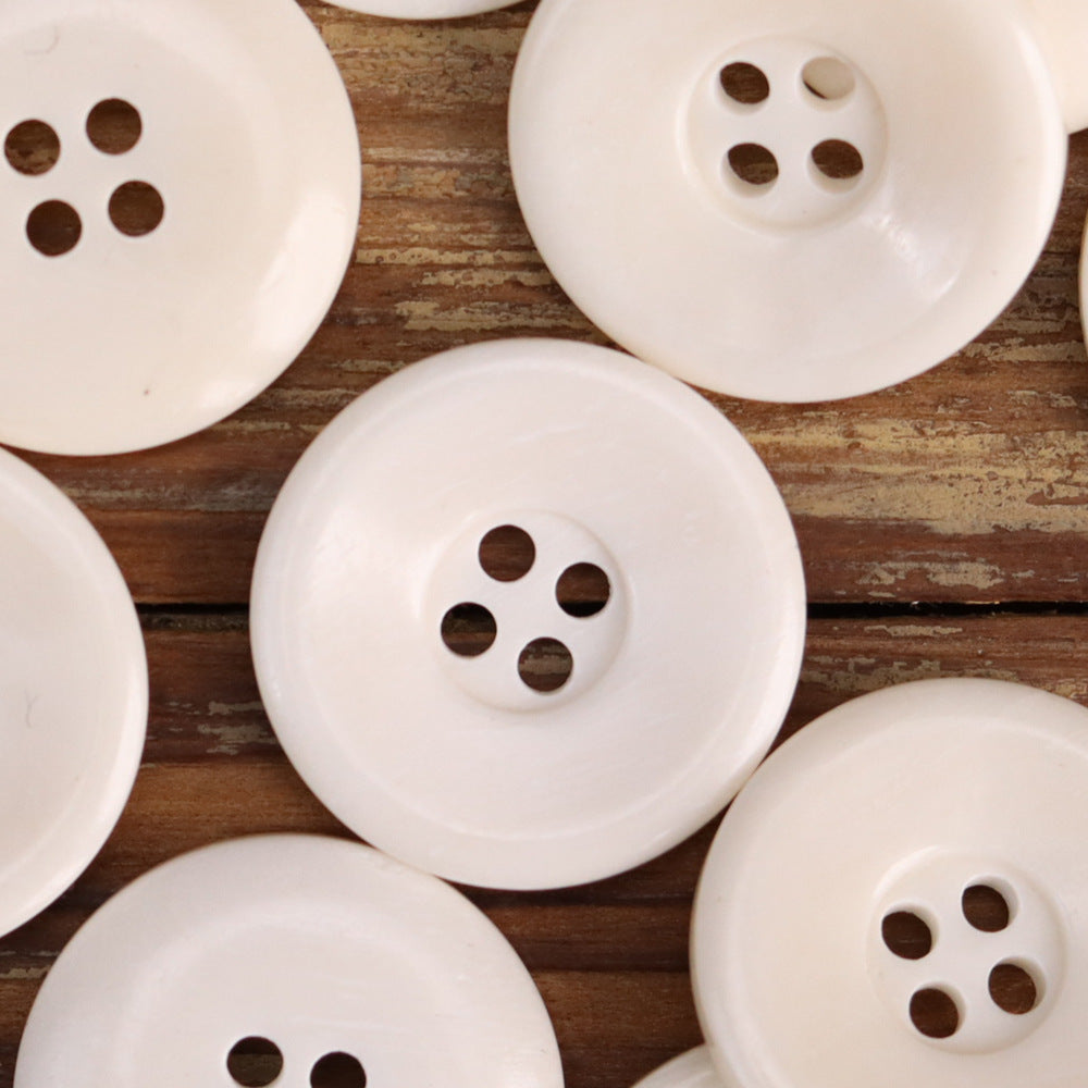 White bowl-shaped distressed bone buttons with 4-hole design, grouped close-up