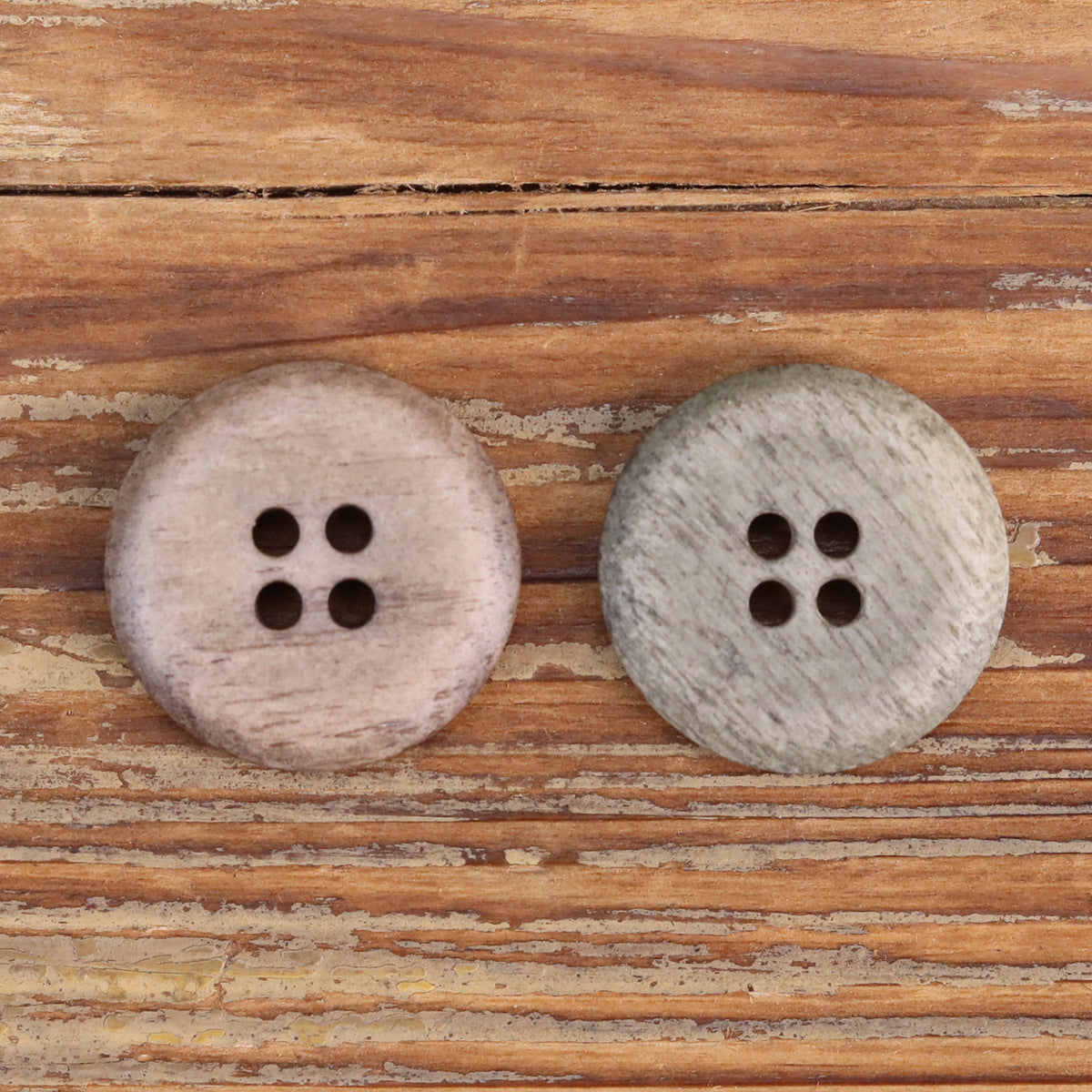 Two round shallow buttons with four holes, light beige and light gray textured finish