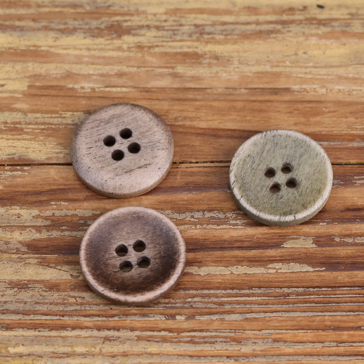 Set of shallow buttons with four holes each, light green/stone tone, textured fronts