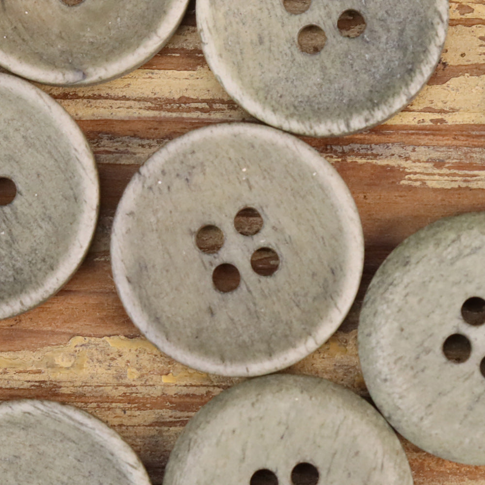 Close-up of textured shallow buttons, four holes each, light green tone