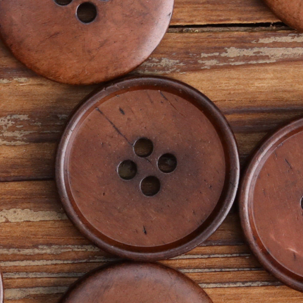 Black four-hole flat button front, round face with four holes, stitched-hole detail.