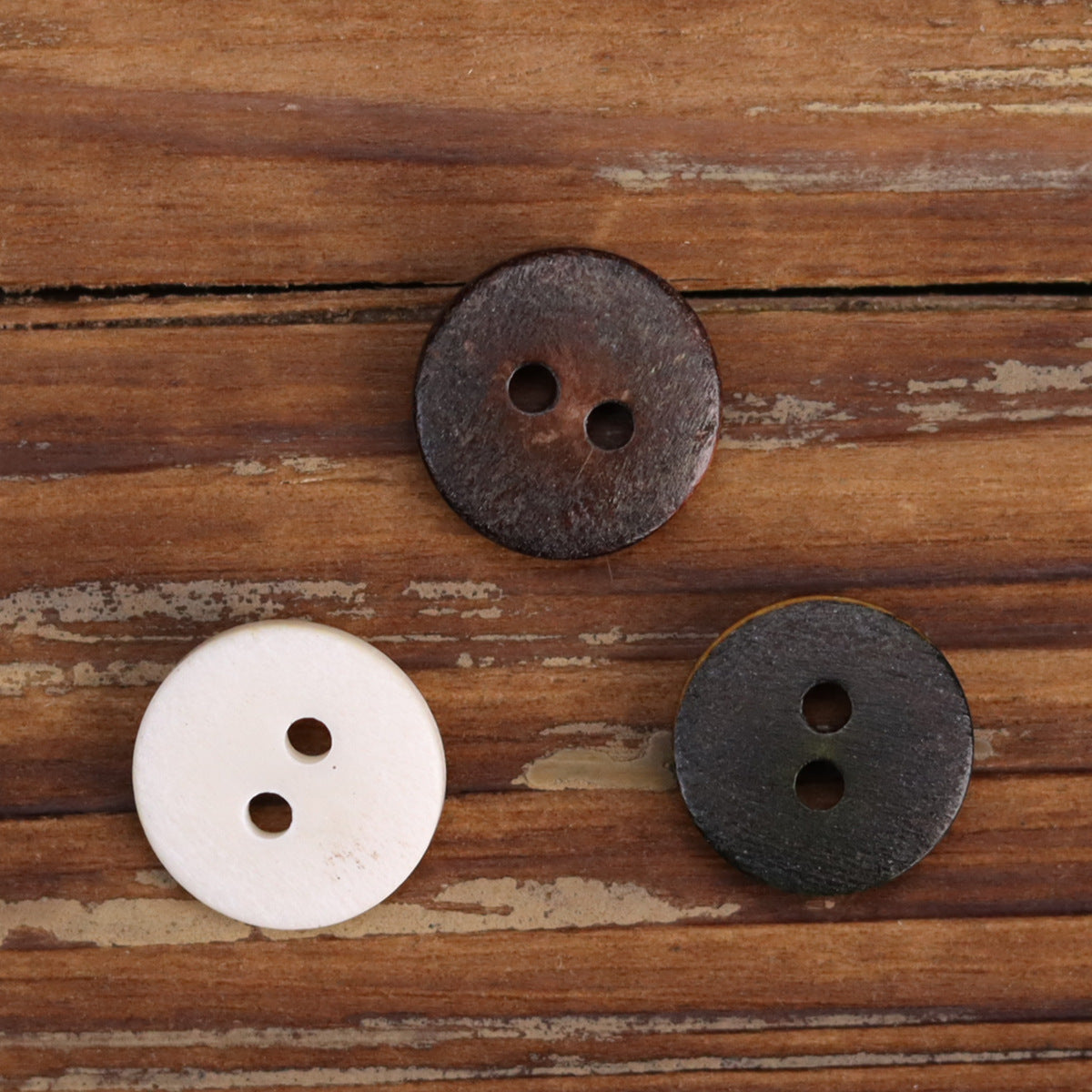 White and dark brown round two-hole shirt buttons with worn bronze rim