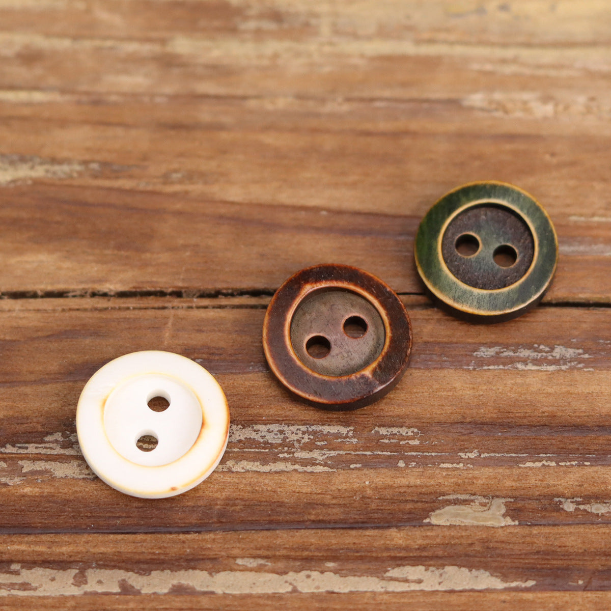 White and brown two-hole shirt buttons with dark backing, plus green button