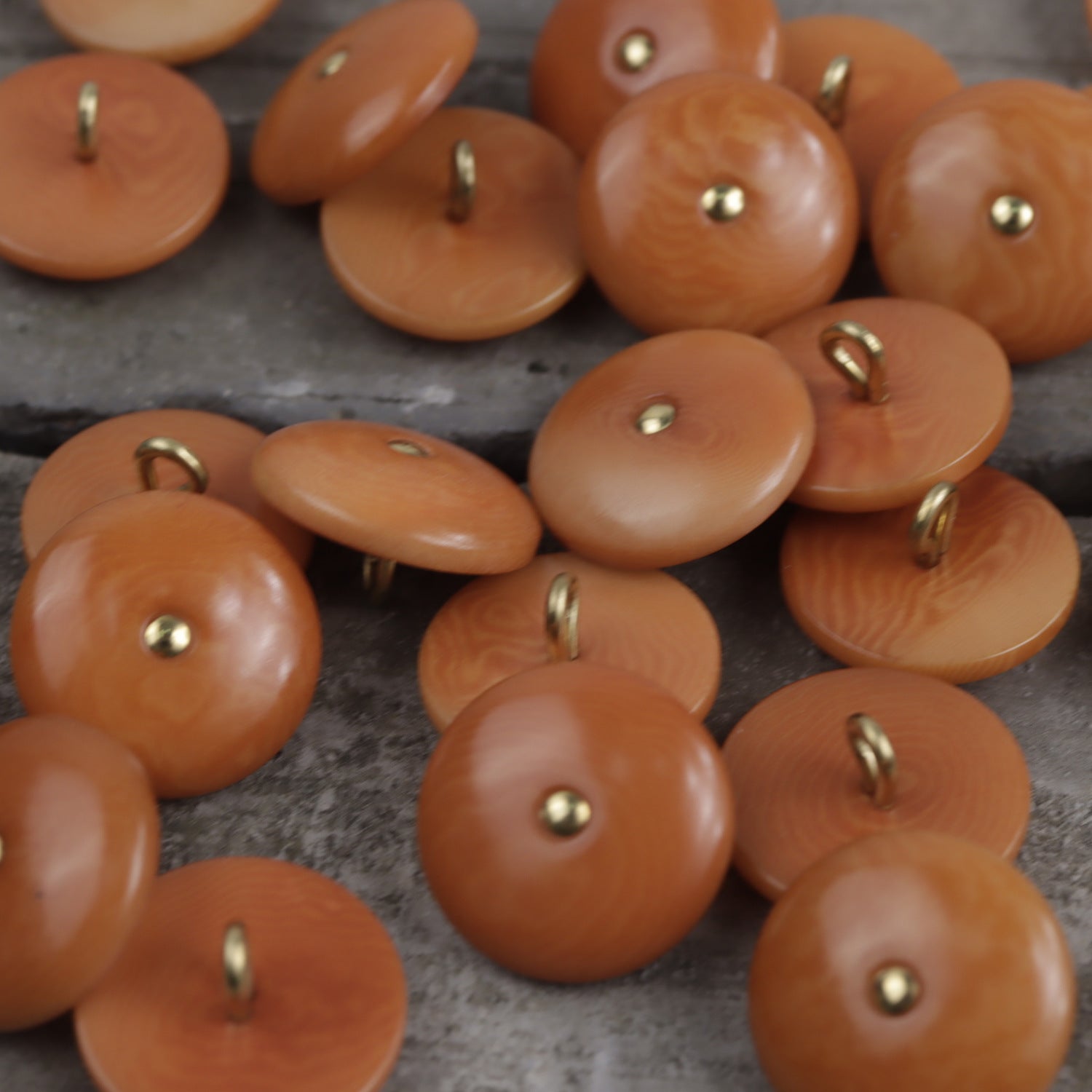 Natural palm nut shank buttons in orange, round with brass shank and center button face.