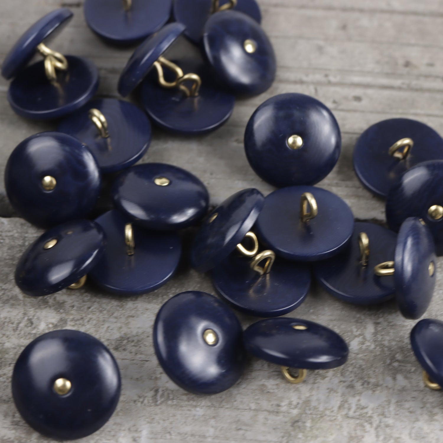 Natural palm nut shank buttons in dark blue, round with brass shank centers.