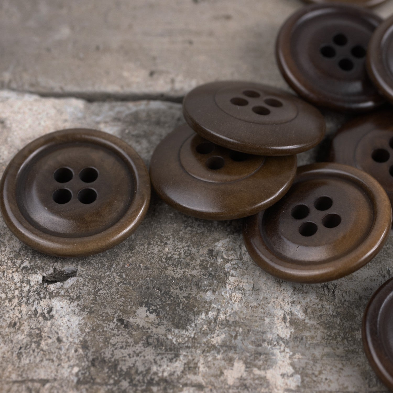 Several dark brown round corozo buttons, each with four holes