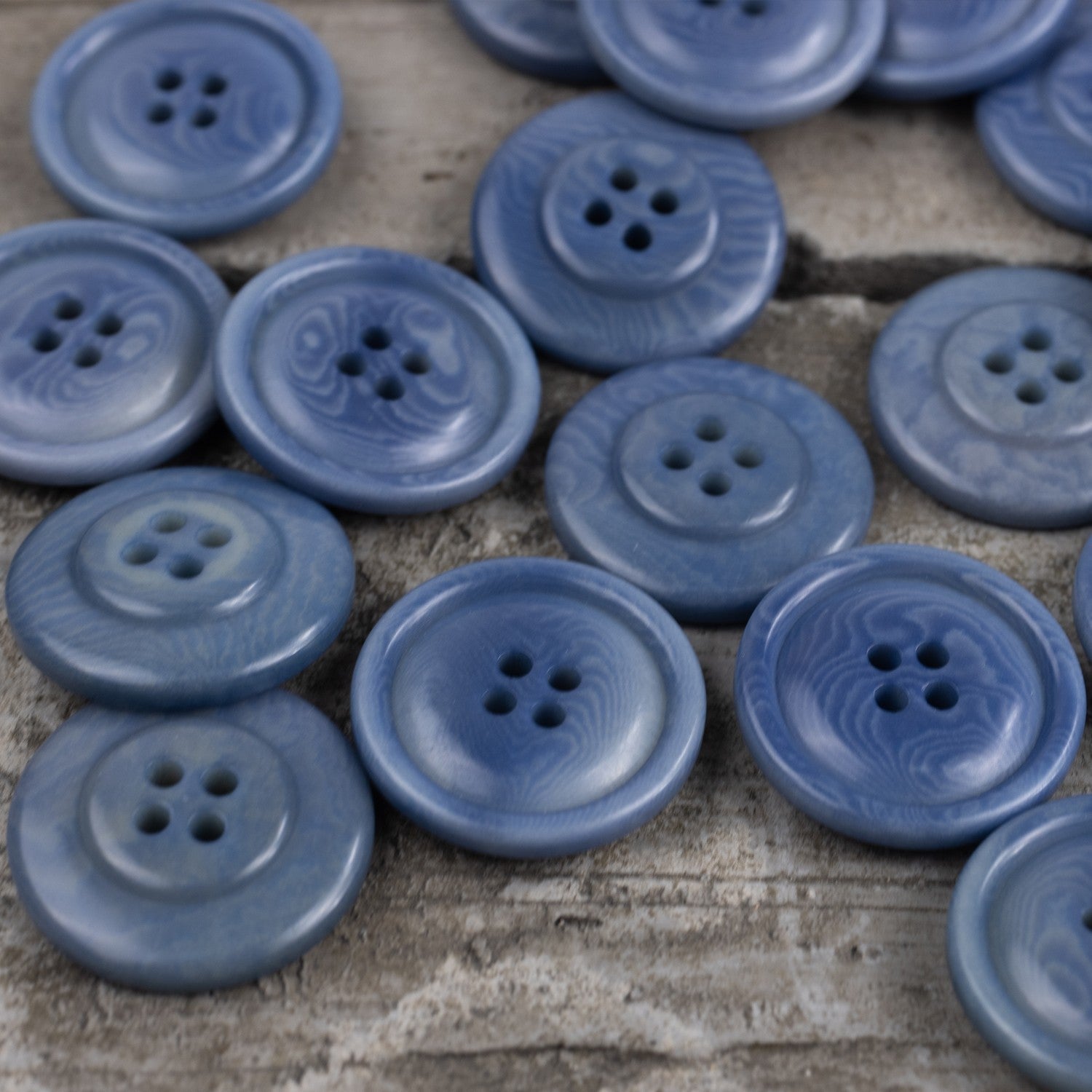 Sky blue round corozo sweater buttons, multiple four-hole designs visible