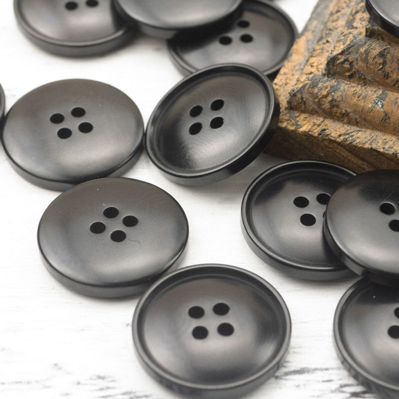 Matte round four-hole buttons in dark gray tones, multiple buttons shown