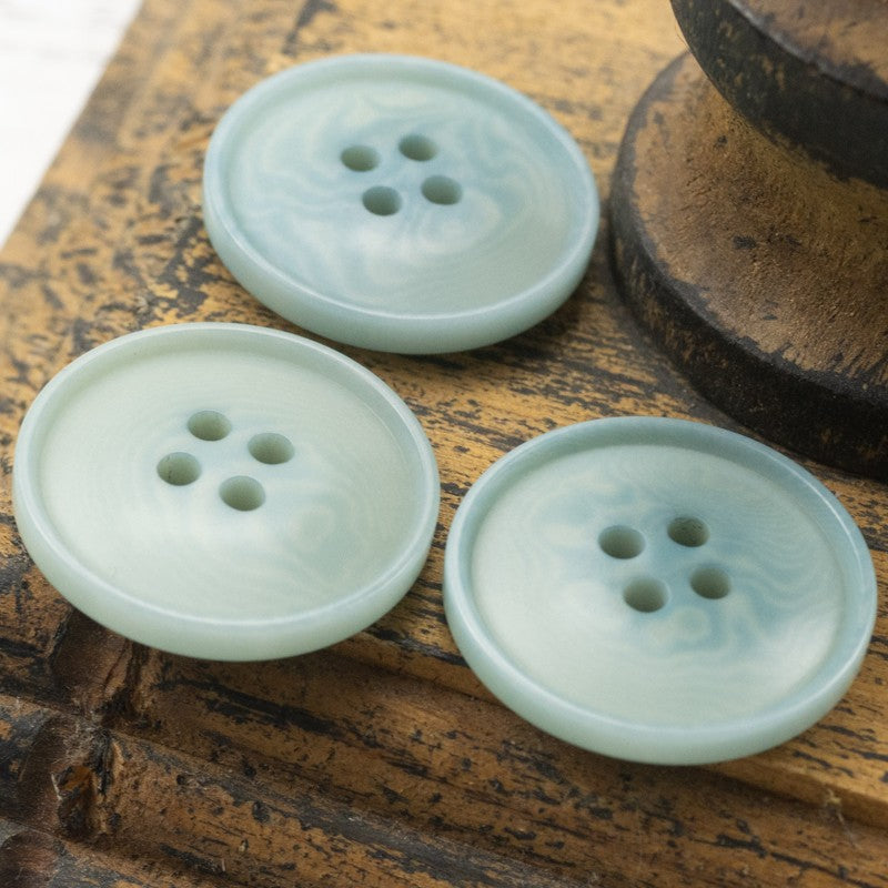 Gray-blue round four-hole palm nut buttons, smooth faces with four holes