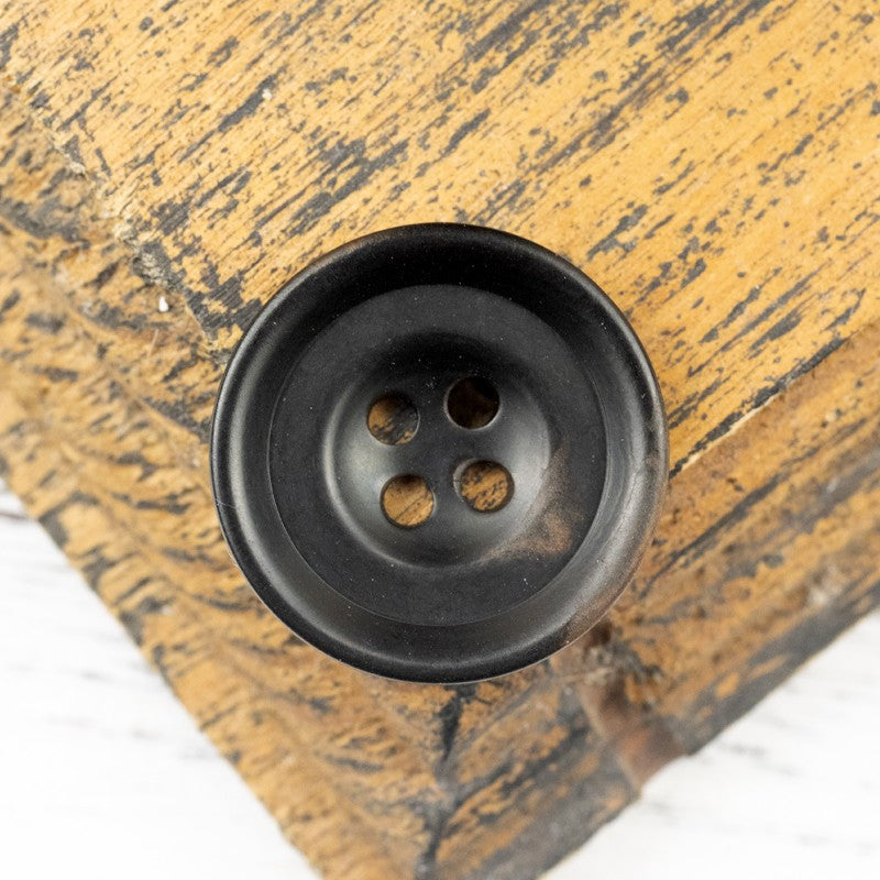 Blue-toned dark nut shell button, four-hole front, natural mottled edges