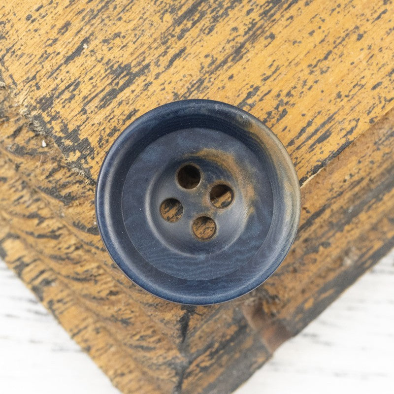 Blue nut shell button, round with four holes, subtle swirl patterns