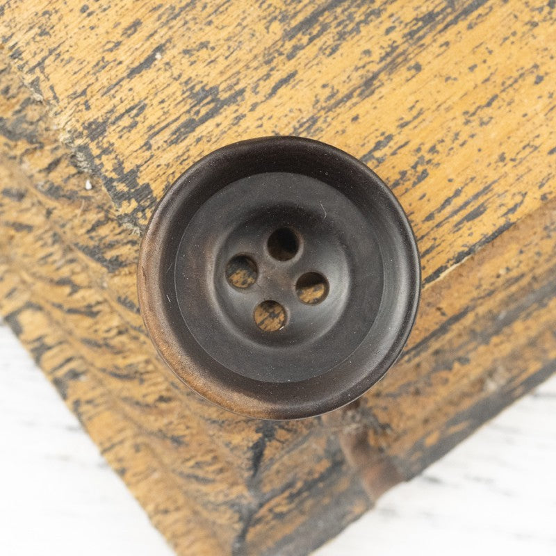 Blue-toned nut shell button, round face with four holes, slight mottling