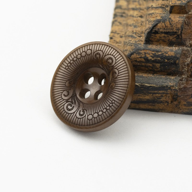 Brown four-hole nut shell button with decorative etched mandala pattern