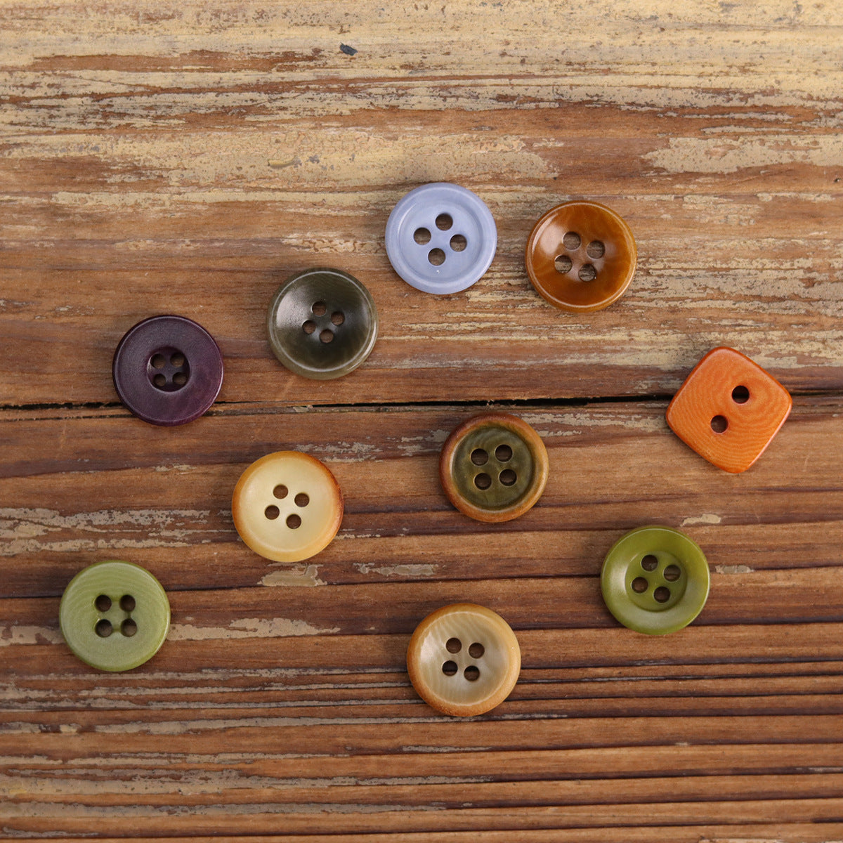 Assorted shirt buttons: pale blue, dark purple, green, tan, bronze, orange, four-hole