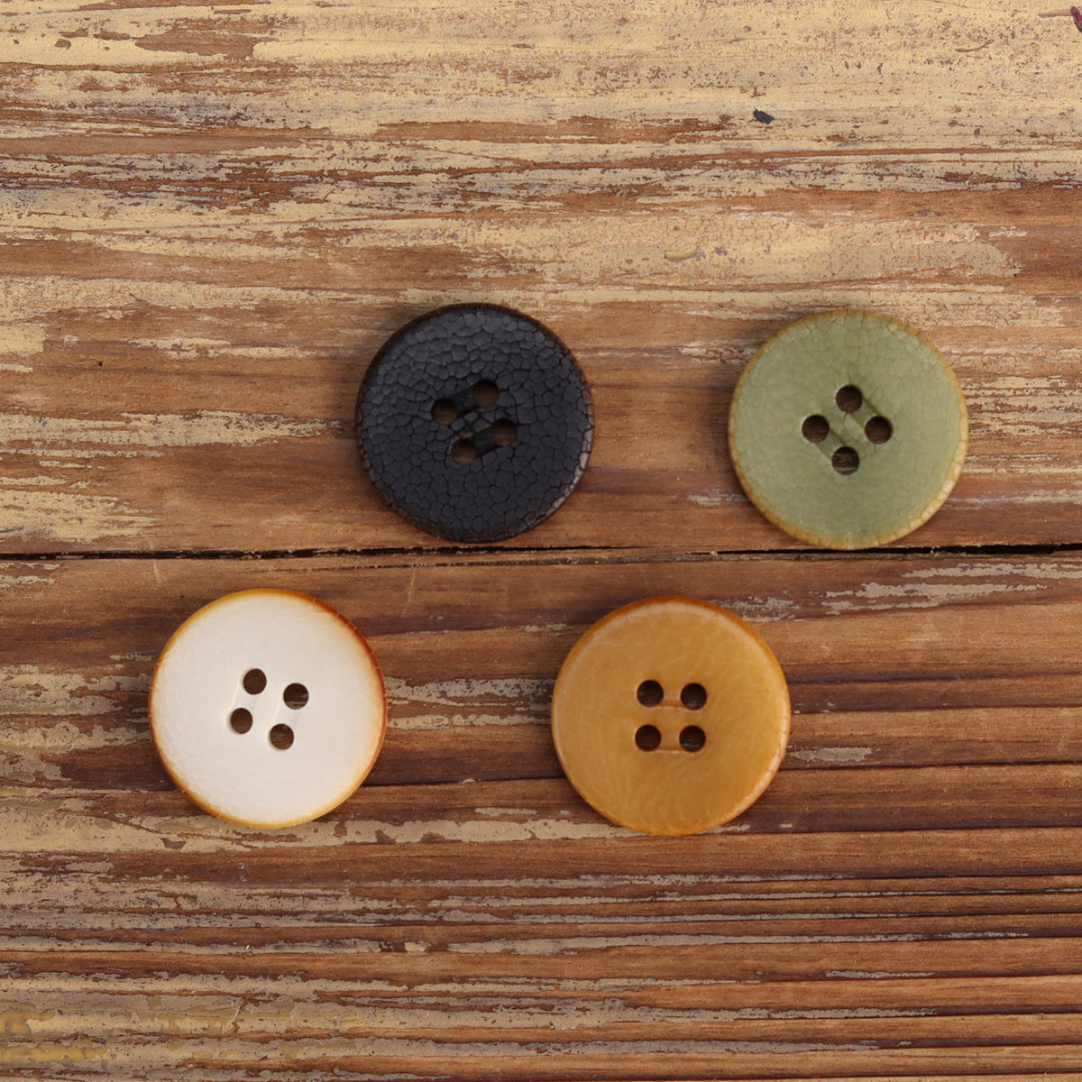 Cracked fruit buttons: dark charcoal, olive green, cream white, and amber/yellow 4-hole