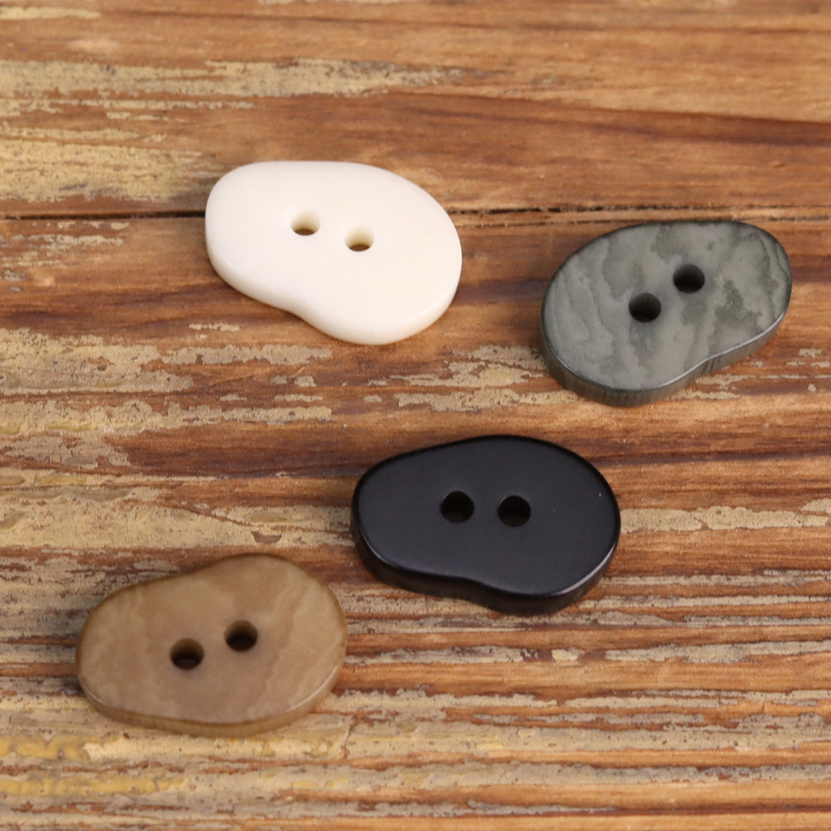 Peanut-shaped fruit buttons: white, gray, and dark, each with two holes