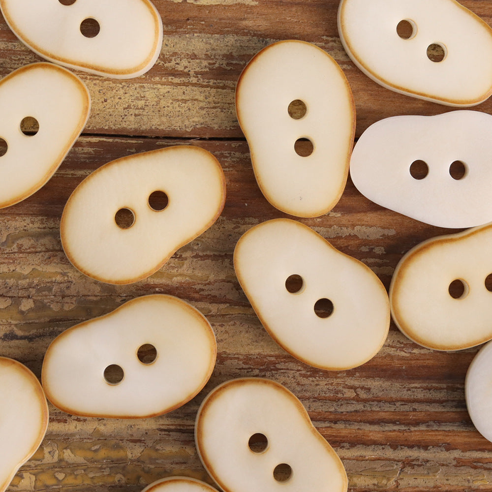 Ivory peanut-shaped fruit buttons with two holes, arranged in a group